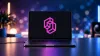 Laptop zeigt das pinke Jev-Logo von TypeSafe auf dem Bildschirm im modernen Neon-Setup